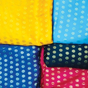 May include: A collection of colorful fabrics, each with a repeating floral pattern. The colors include yellow, light blue, dark blue, dark green, and pink. The fabric appears to be silk or a similar material.
