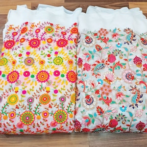Pu&ograve; includere: Due pannelli di tessuto bianco con ricami floreali colorati. Il tessuto a sinistra presenta un motivo ripetitivo di grandi fiori colorati con foglie verdi. Il tessuto a destra presenta un motivo pi&ugrave; intricato di fiori e foglie pi&ugrave; piccoli.
