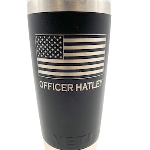 May include: Black Yeti tumbler with a silver lid and base. The tumbler has a laser-etched American flag and the text "OFFICER HATLEY".
