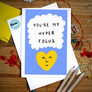 May include: A blue card with a white cloud and the text "You're my hyper focus" in black. A yellow heart with a smiling face is below the cloud.