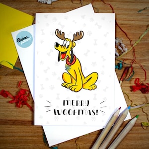 May include: A yellow cartoon dog wearing a red and green Christmas collar with a snowflake charm. The dog has antlers and is sitting on a white background with the text "Merry Woofmas!"