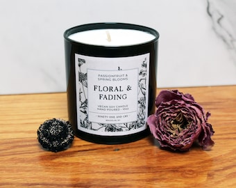 May include: Black candle jar with a white label that reads "Passionfruit & Spring Blooms Floral & Fading Vegan Soy Candle Hand Poured - 100% - Ninety One and Cry - Brooklyn, NY".