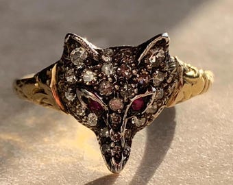 以下が含まれることがあります： ダイヤモンドとルビーの目をセットした狐の頭のデザインの金の指輪です。