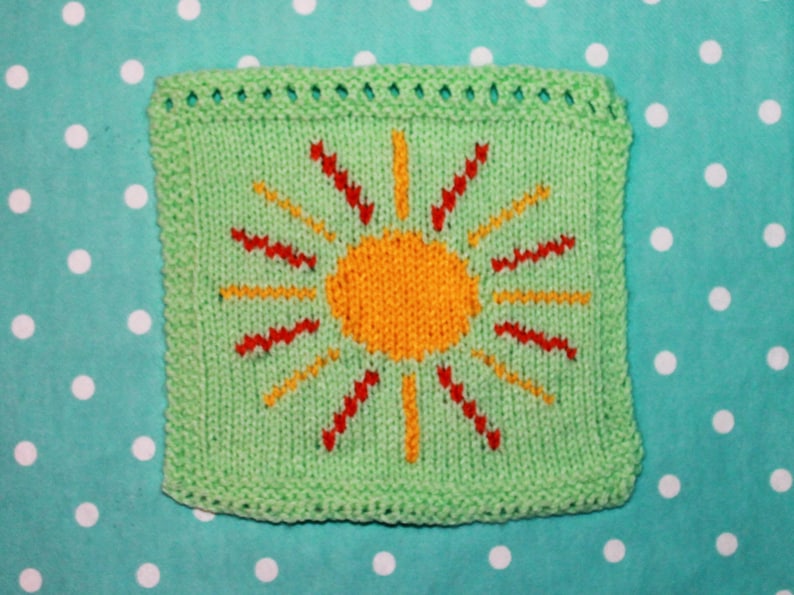Puede incluir: Un cuadrado de punto verde con un sol amarillo y rayos rojos. El sol est&aacute; en el centro del cuadrado y los rayos se extienden hasta los bordes.