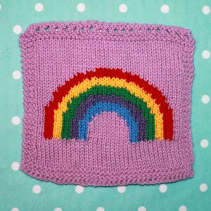 Puede incluir: Un cuadrado tejido con un dise&ntilde;o de arco&iacute;ris en rojo, naranja, amarillo, verde, azul, a&ntilde;il y violeta. El cuadrado es de color morado claro.