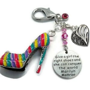 May include: A charm with a high-heeled shoe, heart, and a tag. The shoe is striped in red, yellow, purple, and green. The tag says "Give a girl the right shoes and she can conquer the world Marilyn Monroe."