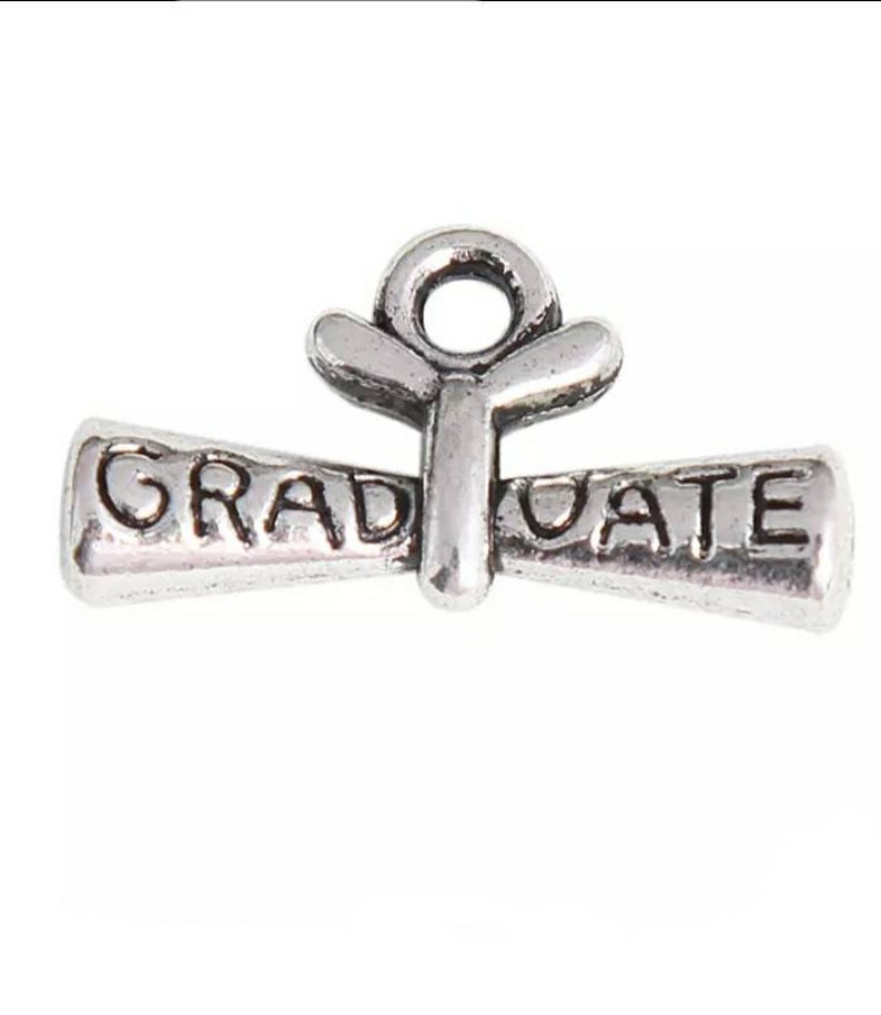 May include: Silver charm in the shape of a graduation cap with the word "GRADUATE" on it.