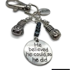 May include: Silver keyring with a round charm that says "He believed he could, so he did". The keyring also has two silver boxing glove charms, a silver charm that says "self-control", and several black beads.