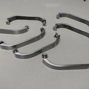 May include: Six silver metal handles with screws. The handles are curved and have a smooth finish.