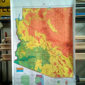 May include: A vintage map of Arizona with a color-coded key showing land elevations. The map is printed on a white background and is rolled up on a wooden dowel.