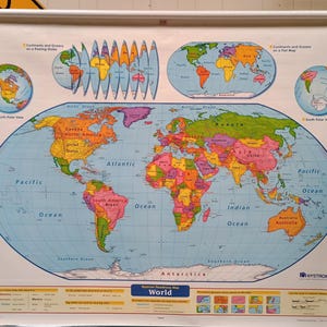 May include: A large, wall-mounted Nystrom World map on a white pull-down roller. The map features a central elliptical projection of the world with colorful continents, blue oceans, and smaller inset maps showing polar views and globe projections.