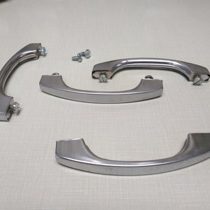 May include: Four silver cabinet door handles with screws. The handles are curved and have a polished finish.