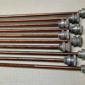 May include: A set of 10 copper colored metal rods with silver colored metal tips. The rods are arranged in a stack with the tips facing the viewer.