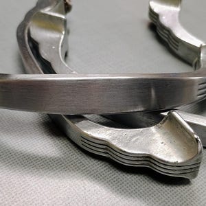 May include: Three silver metal cabinet door handles with a decorative, wavy design.