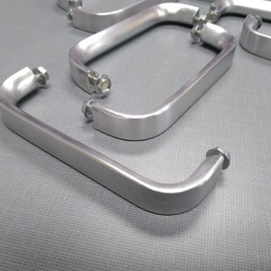 May include: Five silver metal handles with rounded edges and screw holes. The handles are arranged in a staggered pattern.