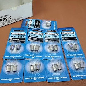 May include: Nine individual blister packs of Rayovac PR2-2 heavy duty flashlight bulbs, each containing two bulbs. The blue and white packaging displays the Rayovac logo, the text Heavy Duty, and 2D Flashlights. A white cardboard box is included.