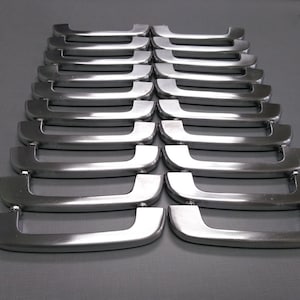 May include: A row of 18 silver-toned metal cabinet door handles. The handles are all the same size and shape, and they have a smooth, polished finish.