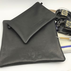 May include: Two black leather pouches with Hebrew text. The larger pouch has the word "שלום" embossed on it. The smaller pouch has the word "לשון" embossed on it.