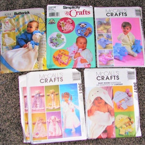 May include: A collection of six sewing patterns for baby items. The patterns are from Simplicity Crafts and McCall's Crafts. The patterns include designs for blankets, hooded towels, and stuffed animals. The patterns are all in white with colorful illustrations.