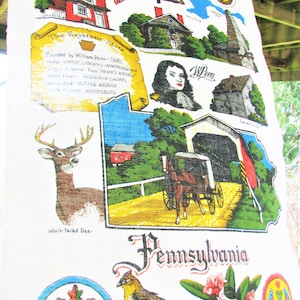 May include: A colorful vintage tea towel featuring a map of Pennsylvania with various state symbols, including the Liberty Bell, a covered bridge, a white-tailed deer, and the state motto "Virtue, Liberty & Independence".