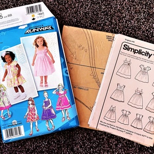May include: Two Simplicity sewing pattern packages for girls' dresses. The pattern numbers are 2265. The patterns are from Project Runway. The patterns include instructions and diagrams for making the dresses.