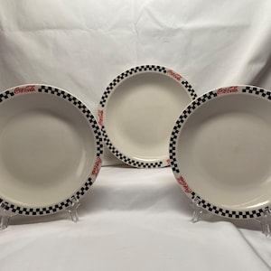3 Coca Cola salad plates by Gibson. preowned. 7 5/8 wide. Black checkered pattern. No chips or cracks. Normal wear from use.