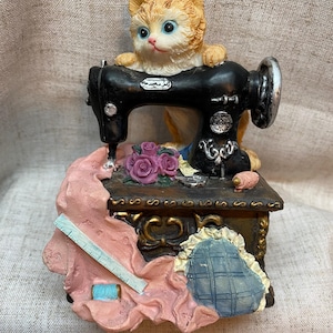 Music box featuring orange cat on sewing machine. Plays very well. excellent preowned condition. Great gift!