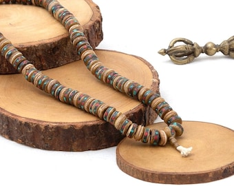 May include: A brown wooden mala necklace with red and turquoise accents, displayed on wooden rounds.