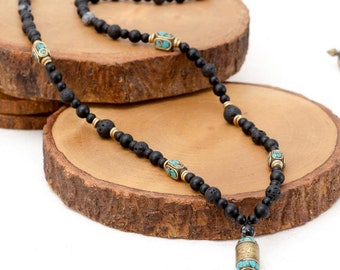 May include: Black lava stone beaded necklace with gold and turquoise accents. The necklace features a small, decorative pendant with a turquoise and gold design.