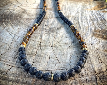 May include: A beaded necklace featuring black lava rock beads, brown tiger eye beads, and gold-colored spacers. The necklace is displayed on a weathered wooden surface, showcasing its natural and earthy tones. The necklace is a stylish accessory.