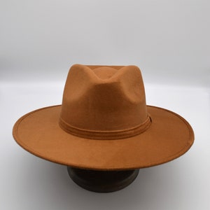 Peut inclure: Un chapeau fedora marron &agrave; large bord. Le chapeau est en feutre et a un design simple.