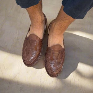May include: A pair of brown leather woven slip-on shoes. The shoes have a woven pattern and a pointed toe.