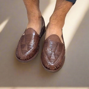 May include: Brown leather sandals with a woven design. The sandals have a closed toe and a flat sole.