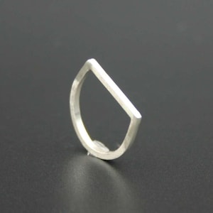 May include: A minimalist silver ring with a unique, geometric design. The ring features a half-circle shape with a straight, flat top, creating a modern and sleek aesthetic. The ring is made of a shiny, metallic material.