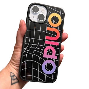 May include: Black phone case with a grid pattern and the word "opiuo" in a gradient of orange, pink, and purple. The case is held in a hand, showcasing the design and the phone's camera.
