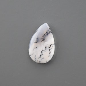 Op de afbeelding: Een witte en zwarte dendritische opaal cabochon in een traanvorm.