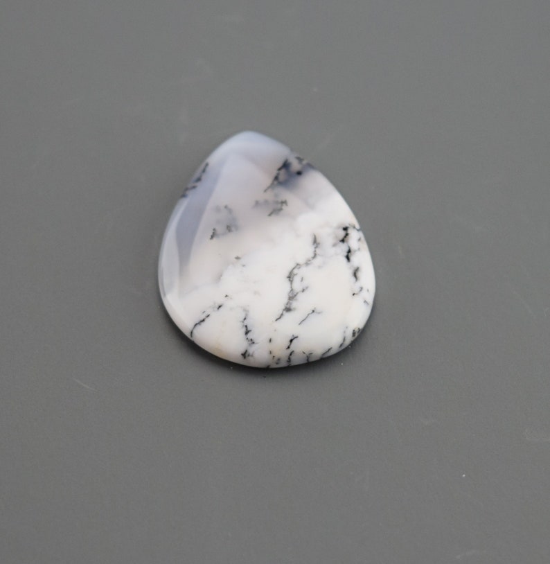 Op de afbeelding: Een witte en zwarte dendritische agaat cabochon in een traanvorm.