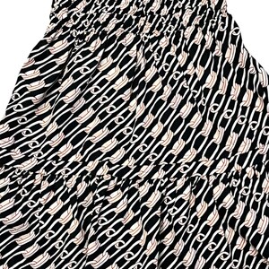 Puede incluir: Vestido estampado en blanco y negro con dise&ntilde;o de eslabones de cadena. El vestido presenta un corpi&ntilde;o ajustado con fruncidos y una falda fluida. El estampado incluye eslabones de cadena blancos y beige sobre fondo negro. El vestido tiene mangas cortas.