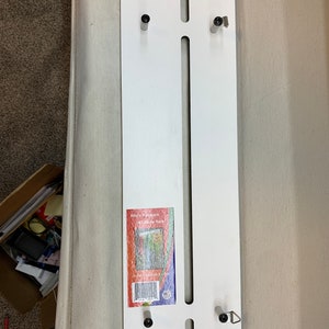 May include: White metal wall mount with four black screws and a label that reads "Rita's Riches, 12-1/2" Door Rack, www.ritariches.com".