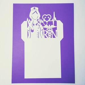 May include: White paper cut-out of a nurse with a stethoscope, heart, and the letters "RN" on a purple background.
