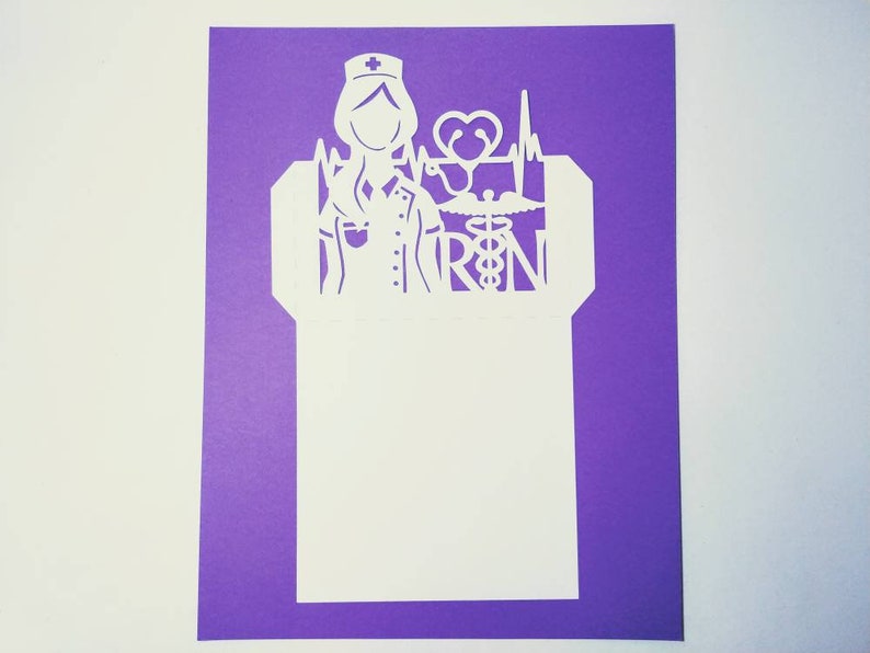 May include: White paper cut-out of a nurse with a stethoscope, heart, and the letters "RN" on a purple background.