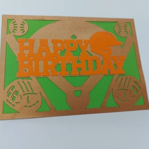 May include: A green and gold baseball-themed birthday card with the words "Happy Birthday" in orange letters.