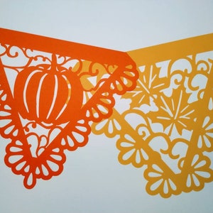 May include: Two orange and yellow paper cutouts in the shape of triangles with intricate designs. The orange cutout features a pumpkin and leaves. The yellow cutout features leaves and swirls.