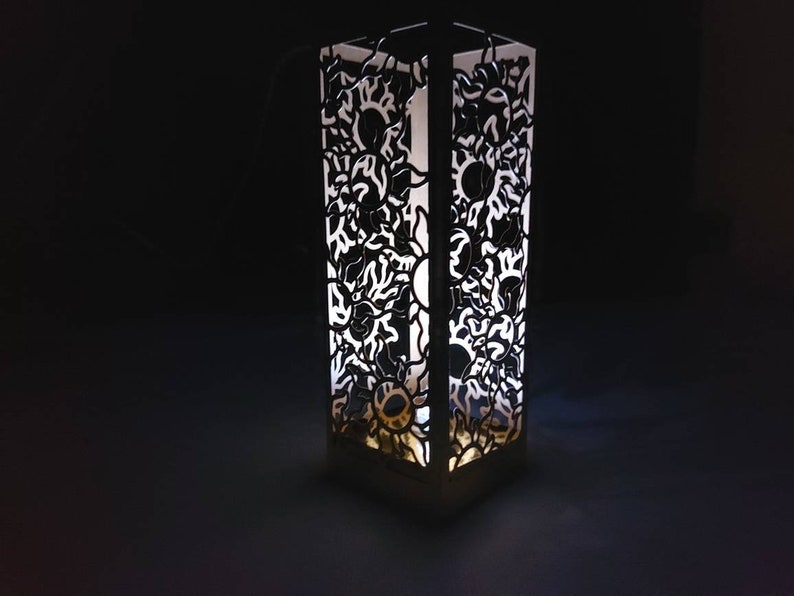 May include: A white, decorative lamp with a geometric design. The lamp is made of a translucent material and has a light inside, casting a warm glow.