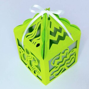 May include: A green paper gift box with a white ribbon. The box has a cut-out design of a mermaid and waves.