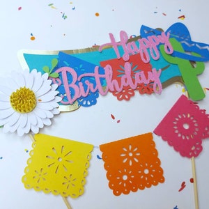 May include: A set of colorful paper decorations for a birthday party. The decorations include a banner that says "Happy Birthday", a flower, and a string of flags with a cut-out design.