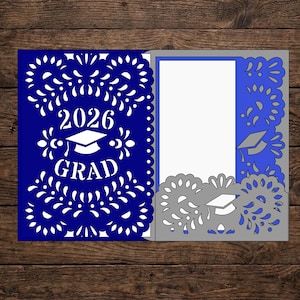 May include: A blue and gray graduation card with intricate cut-out designs. The card features the year "2026" and the word "GRAD" with a graduation cap. The inside of the card is white, ready for a personalized message.