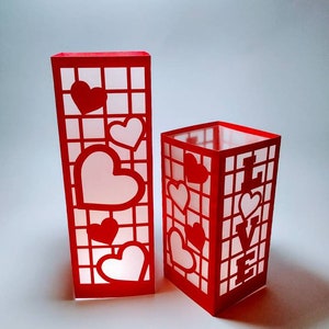 May include: Two red paper lanterns with cut-out hearts and a grid pattern. One lantern has the word "LOVE" cut out on the front.