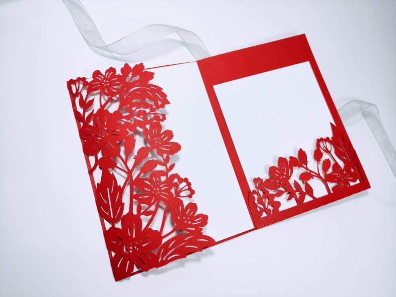 Pu&ograve; includere: Carta d'invito rossa tagliata al laser con un design floreale. La carta &egrave; piegata a met&agrave; e ha un inserto bianco.
