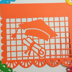 Op de afbeelding: Oranje papieren banner met een afstudeerhoed en diploma uitgesneden. De banner heeft een gegolfde rand en een rasterpatroon.